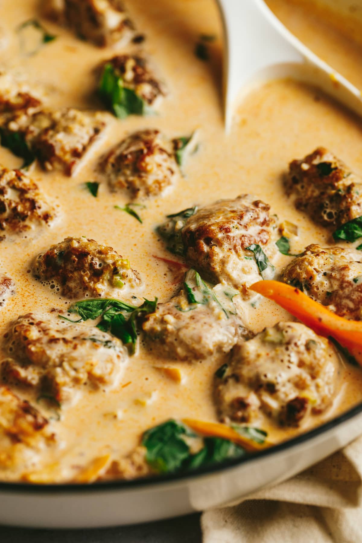 Closeup of turkey meatballs in curry sauce with garnish of basil.