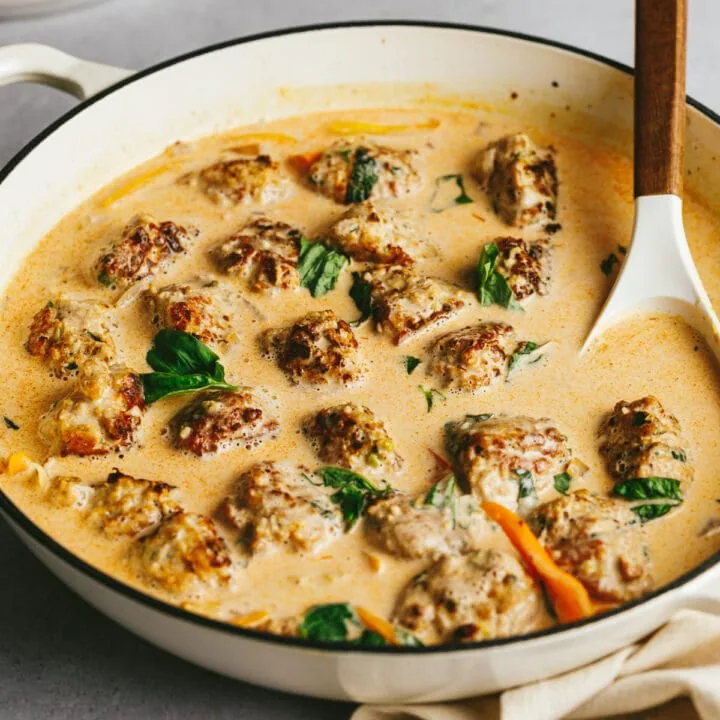 Keto turkey meatballs in a creamy red curry sauce with a spoon.