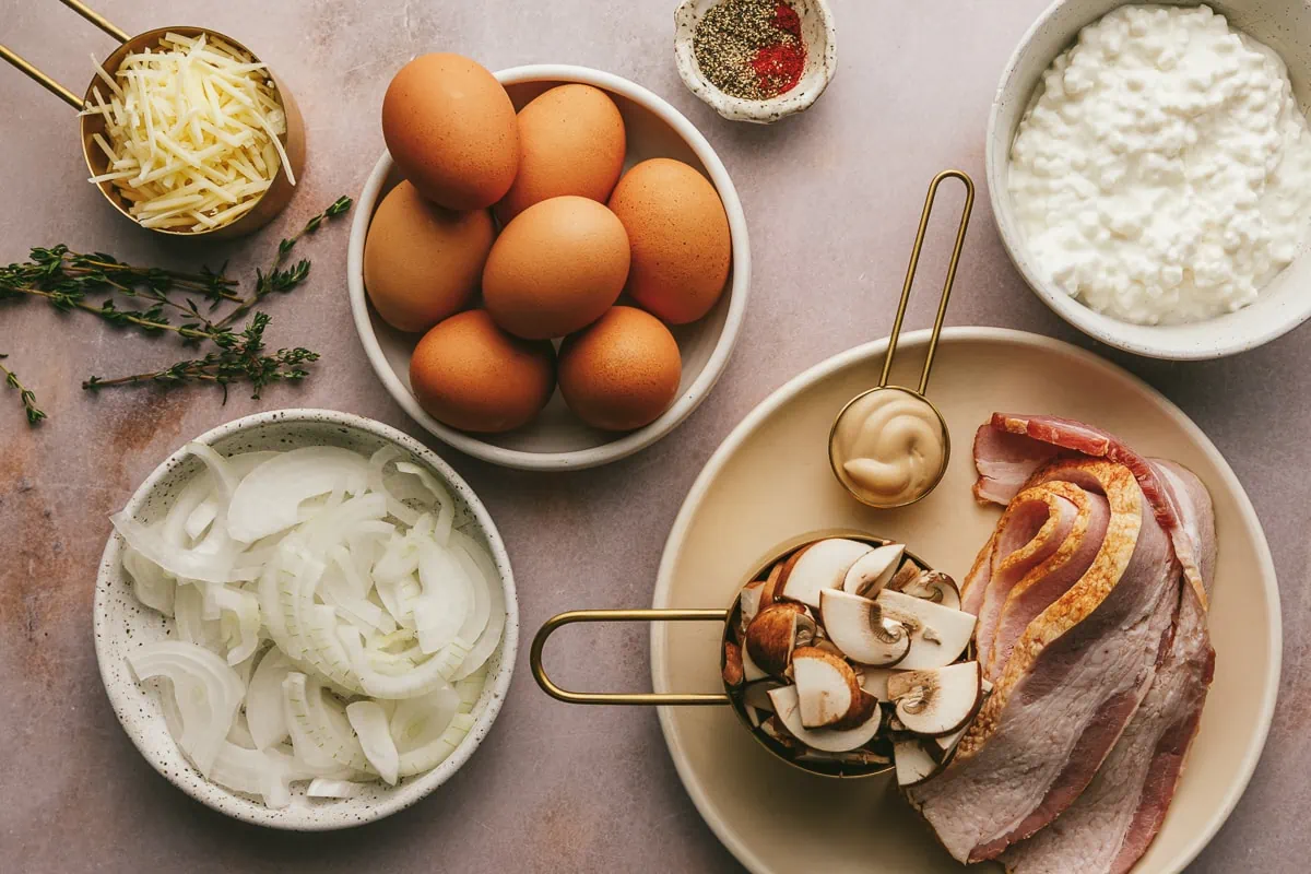 Ingredients for cottage cheese quiche on a pink marble surface.