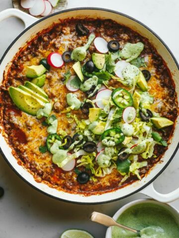 A keto taco casserole loaded with fresh radishes, olives, cilantro, lettuce.