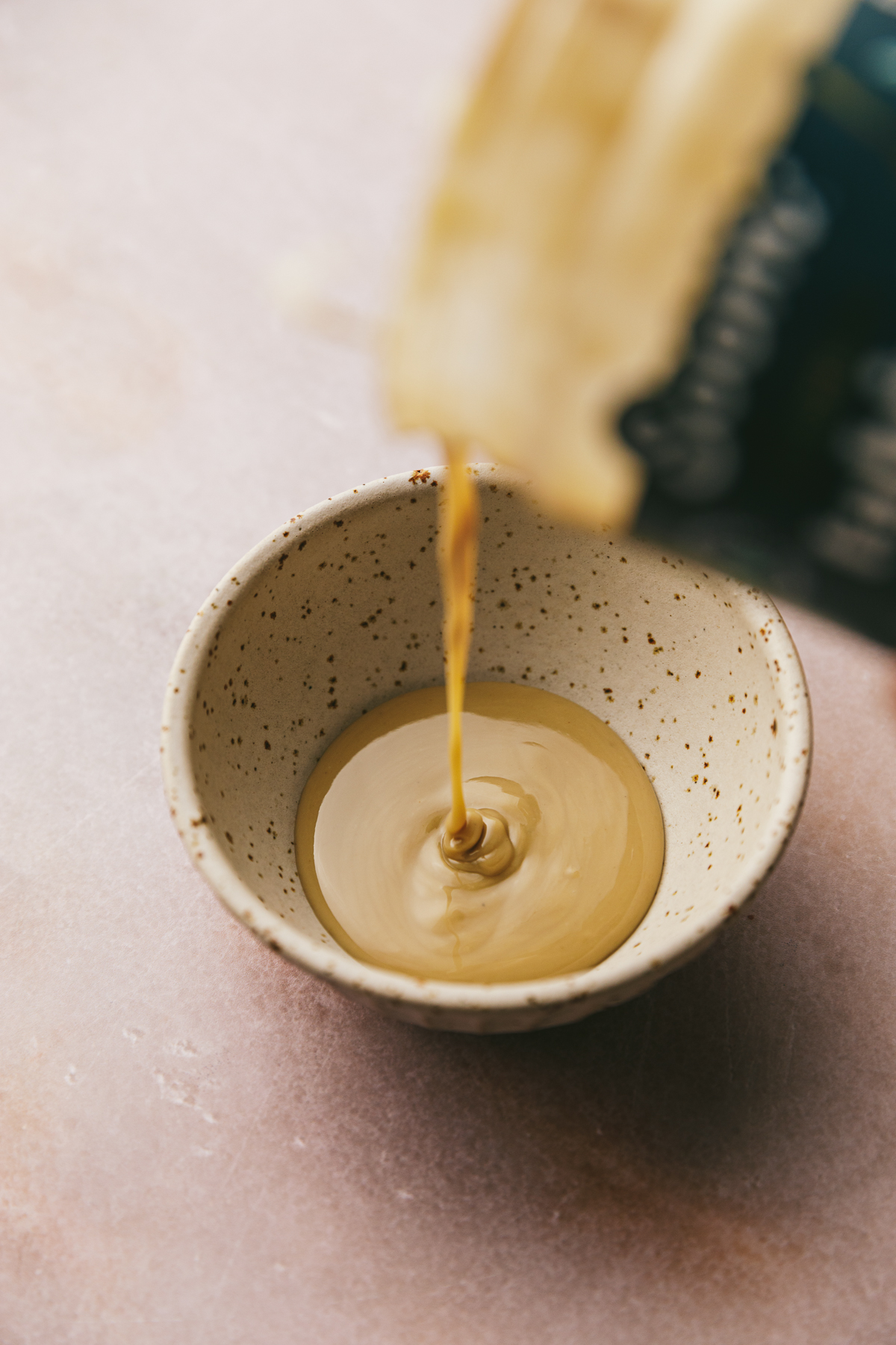 Pouring tahini into a small bowl.