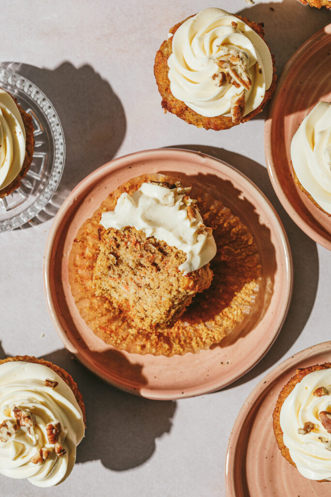 A keto carrot cake cupcake on a pink plate with others around it.