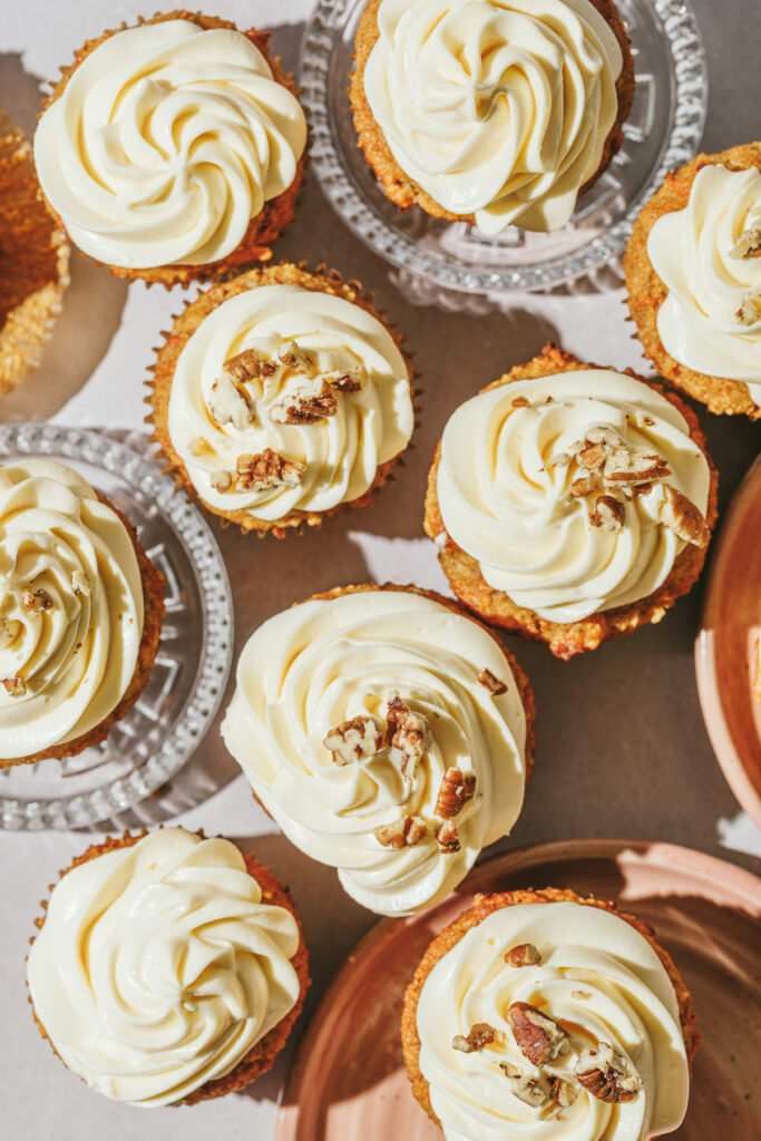 Looking down on several frosted keto carrot cake cupcakes on a countertop.