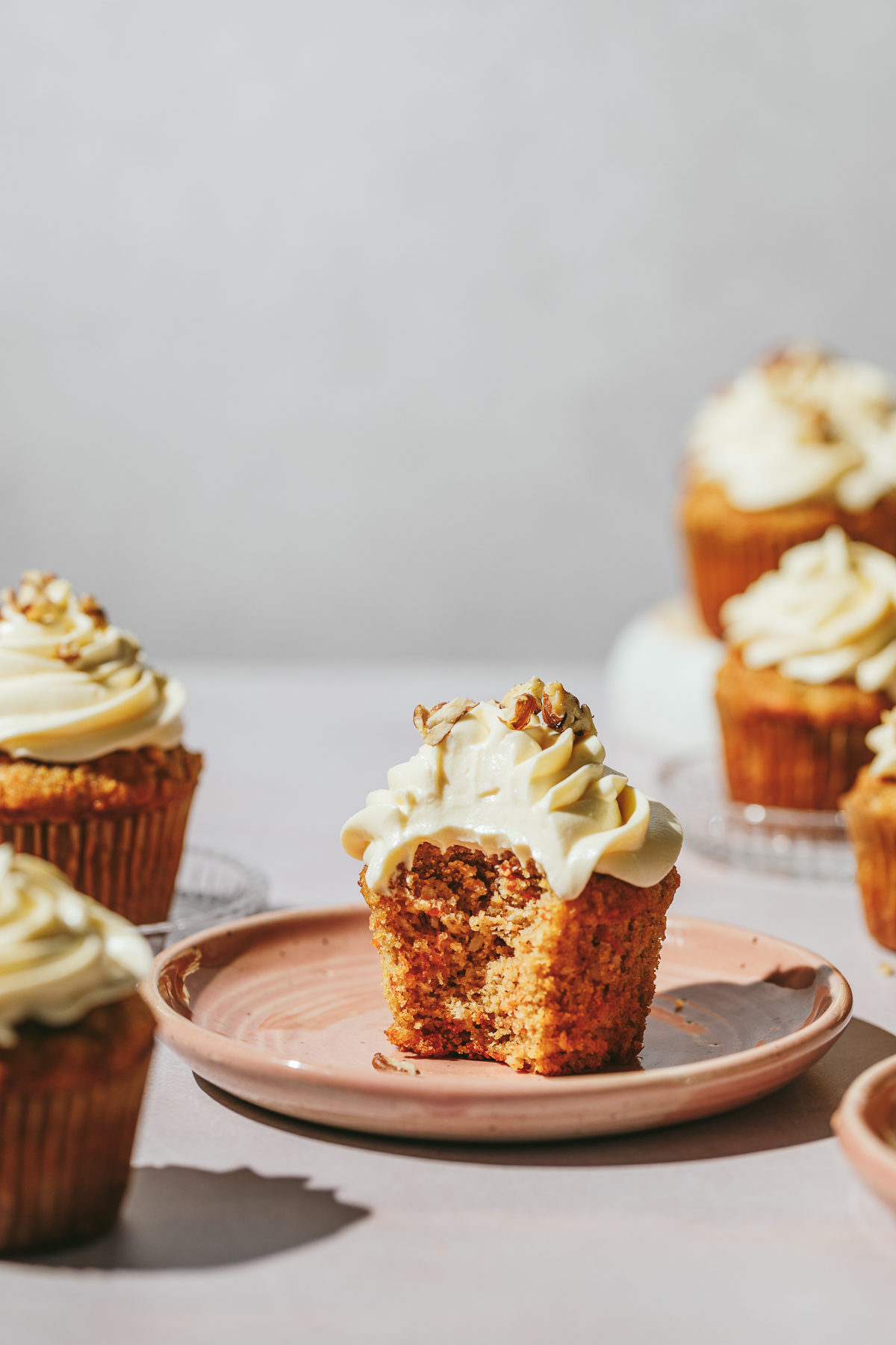 A keto carrot cake cupcake on a pink plate with a bite taken out of it.