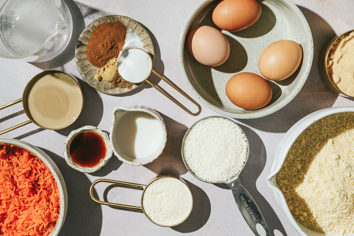 Ingredients arranged on a pink marble surface for carrot cake cupcakes.