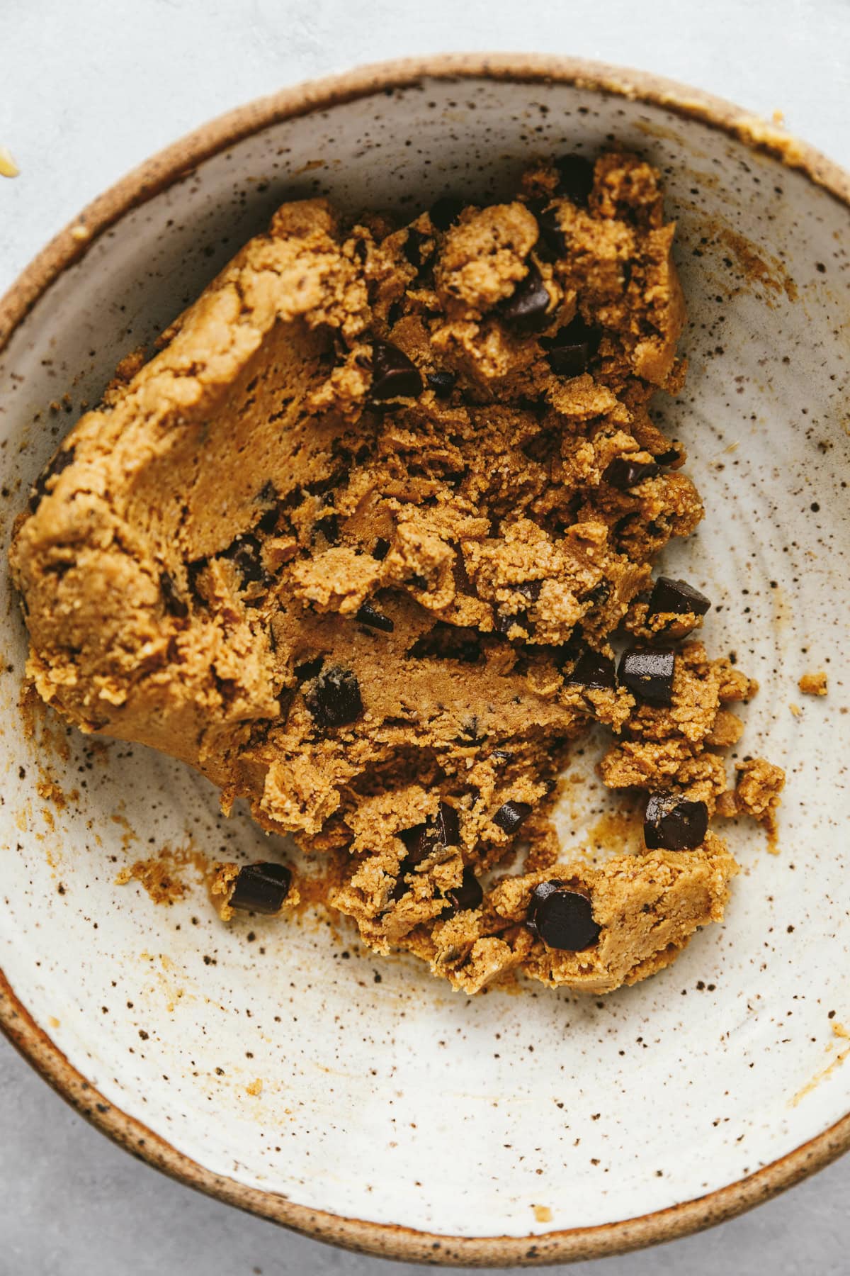 Cookie dough in a white speckled bowl.