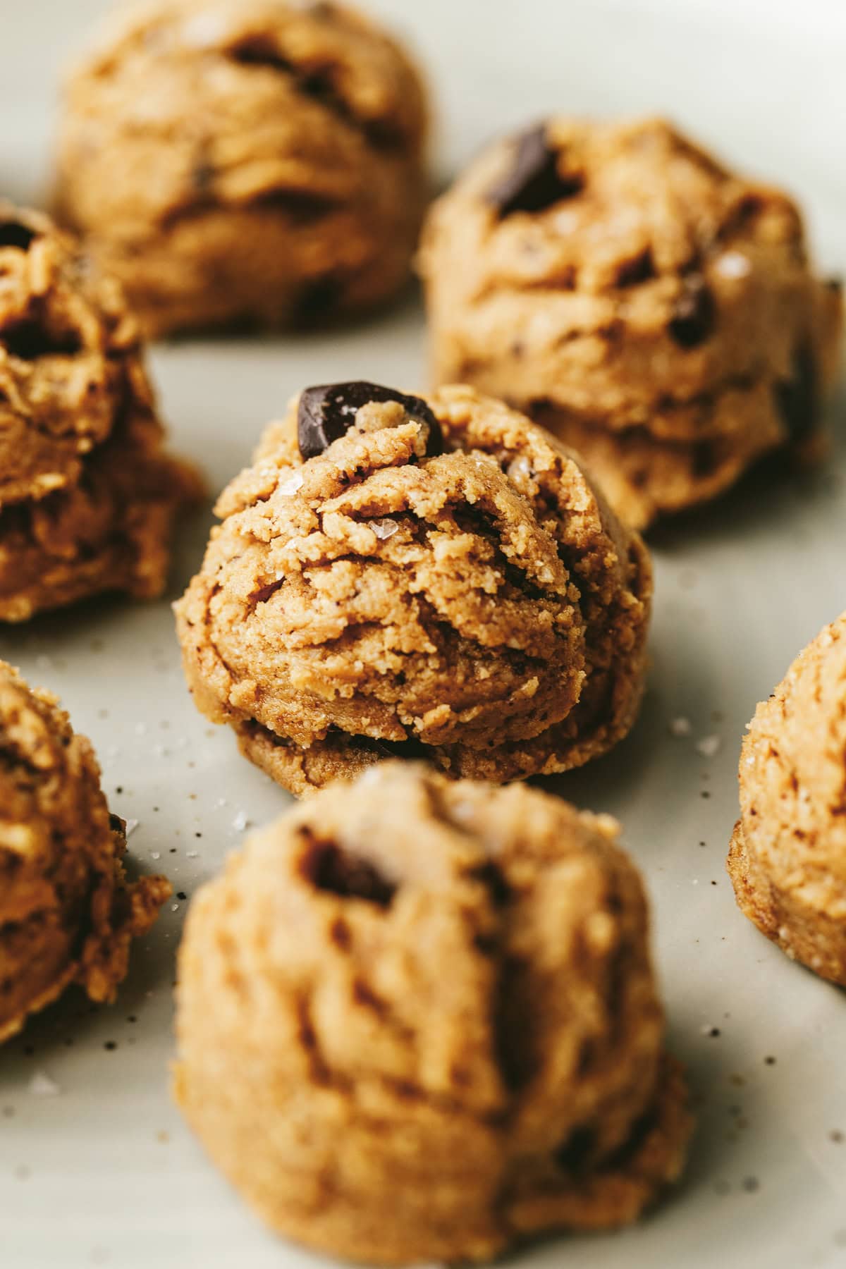 Straight on shot of several cookie dough protein balls on a light sage plate.