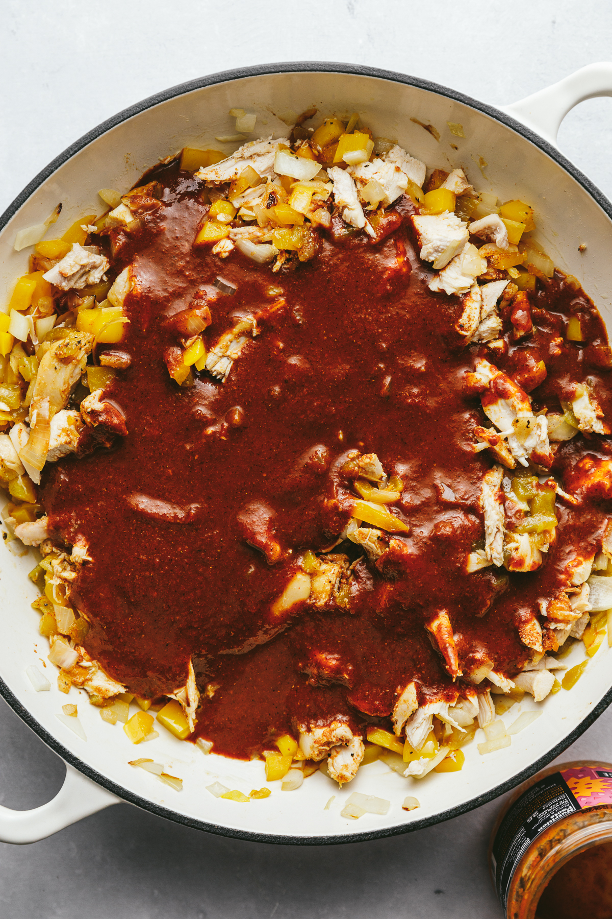 Siete red enchilada sauce on top of the chicken, onion and bell pepper mixture.