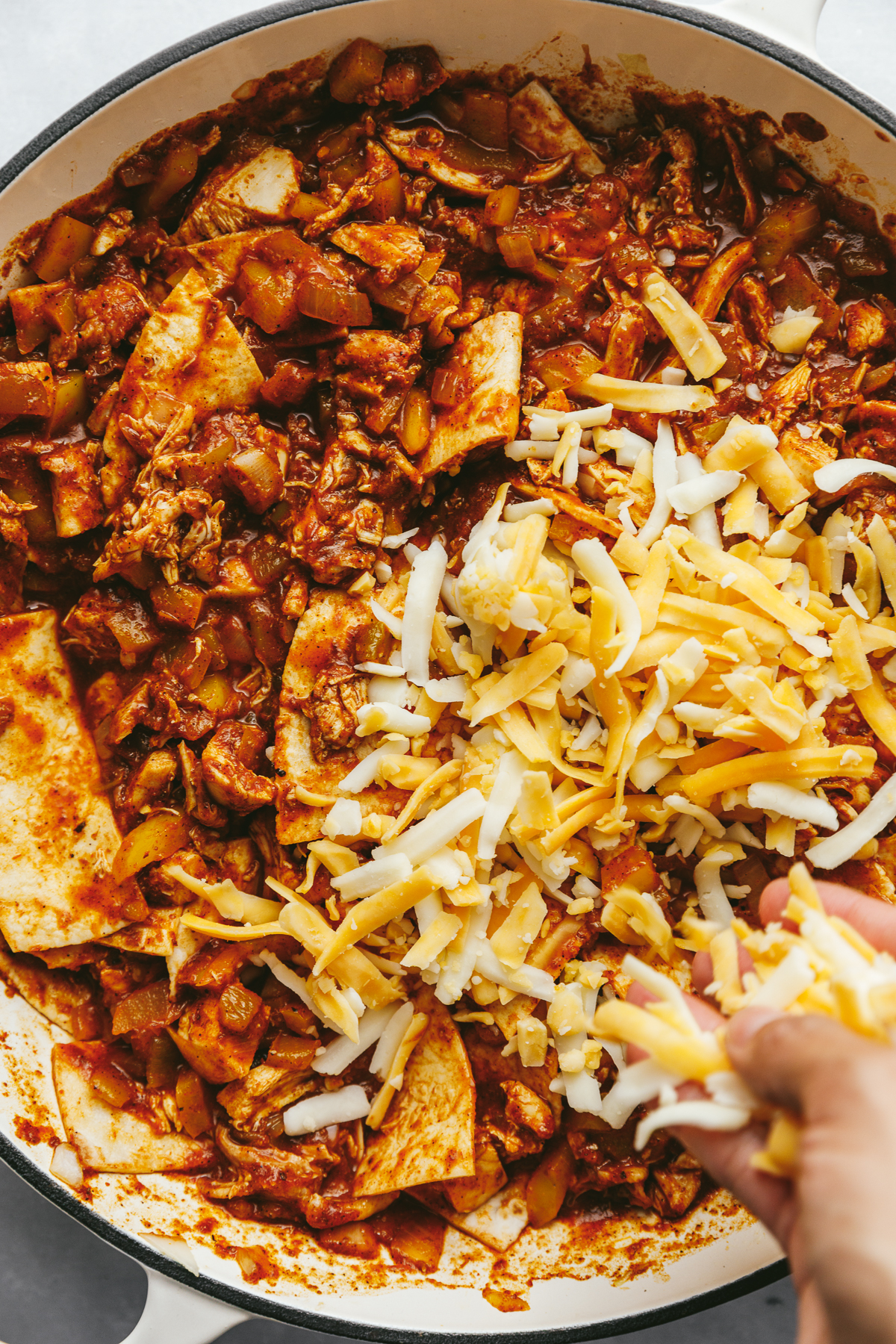 Cheese being scattered on top of the filling for the low-carb chicken enchilada skillet.