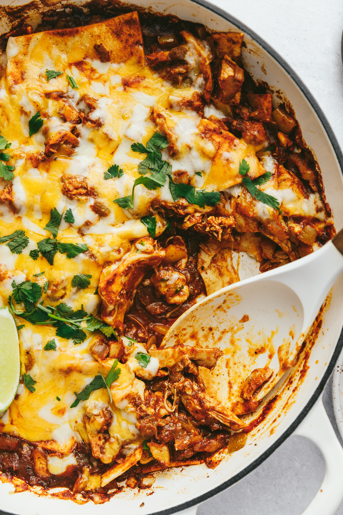Closeup of a white spoon scooping out a portion of keto chicken enchilada skillet.