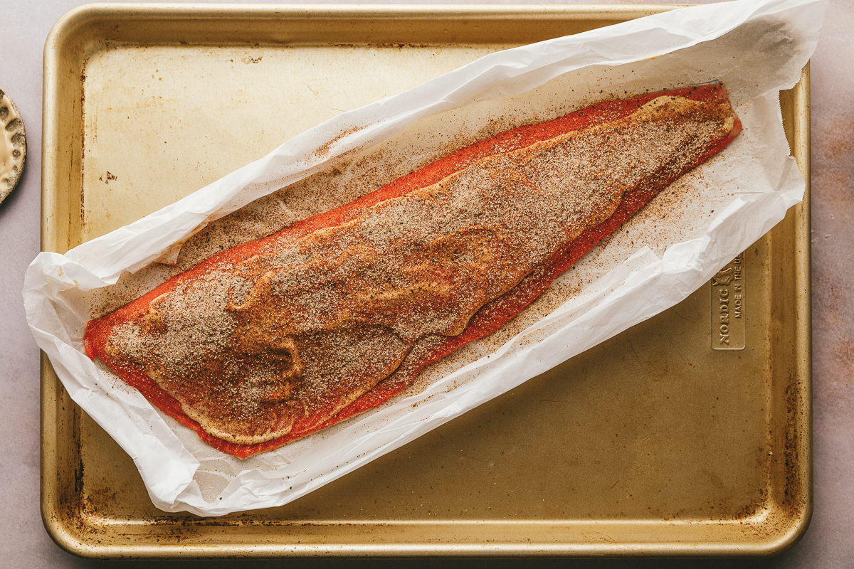 A filet of salmon with seasonings and Dijon sprinkled on top.