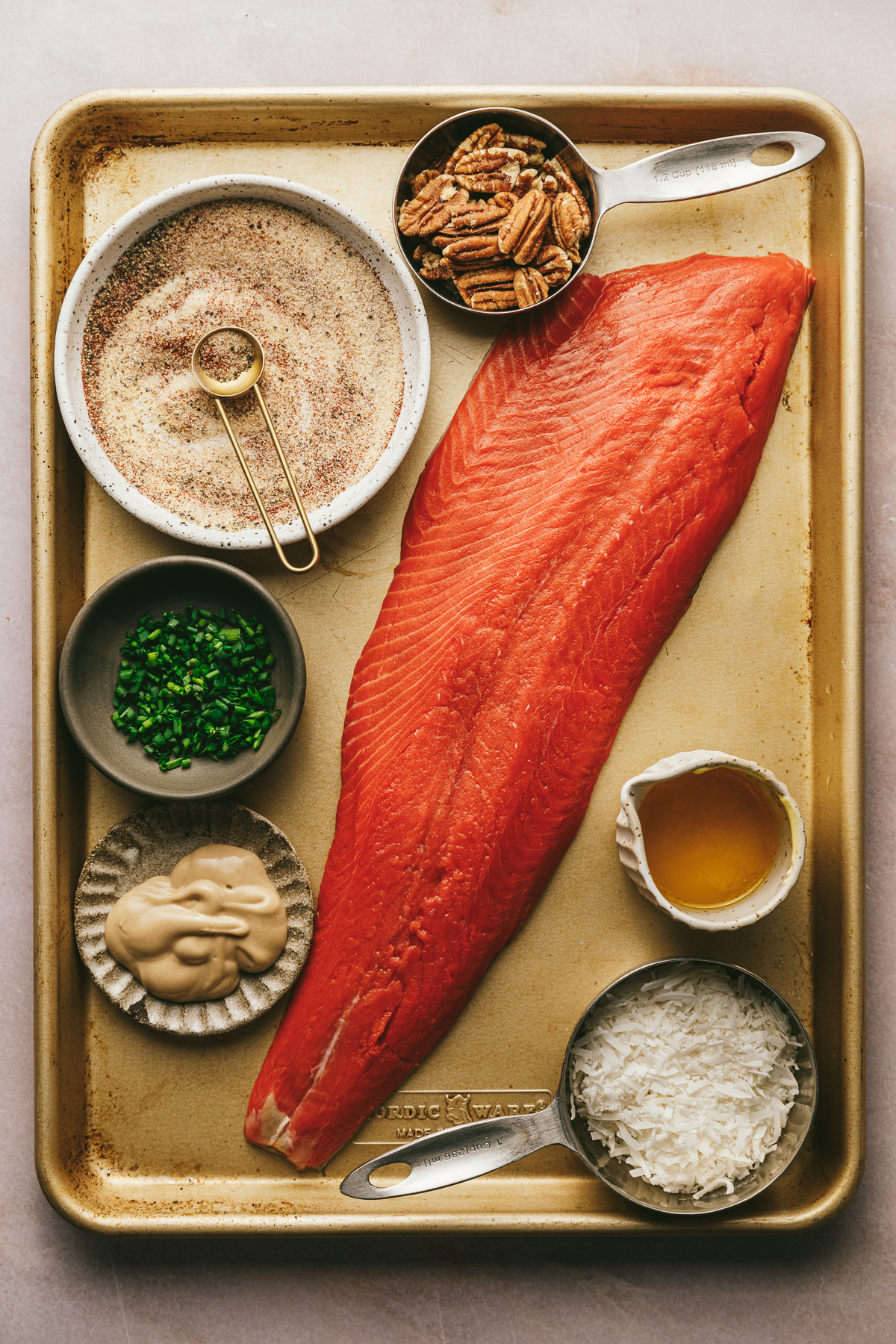 Ingredients for pecan coconut crusted salmon on a gold baking sheet.