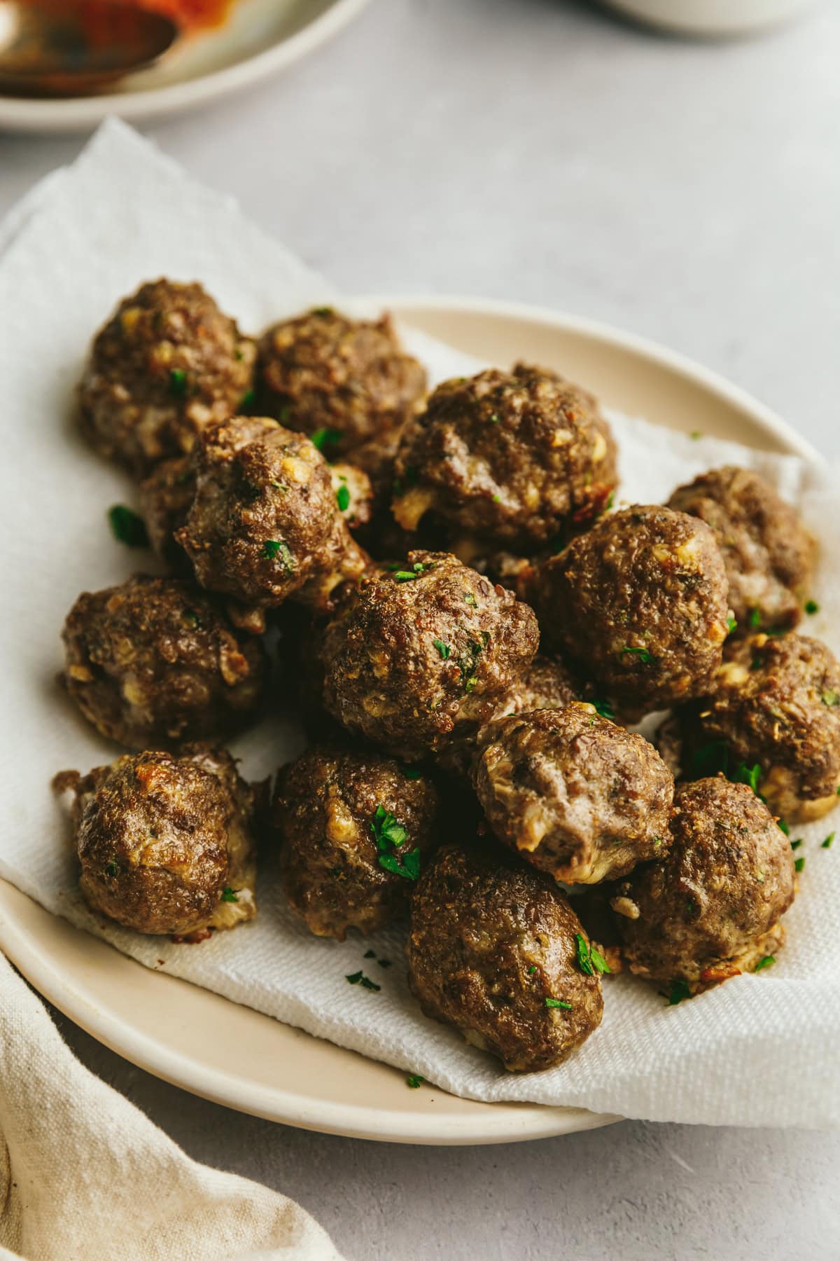 Low-carb meatballs on a plate with a paper towel underneath them.