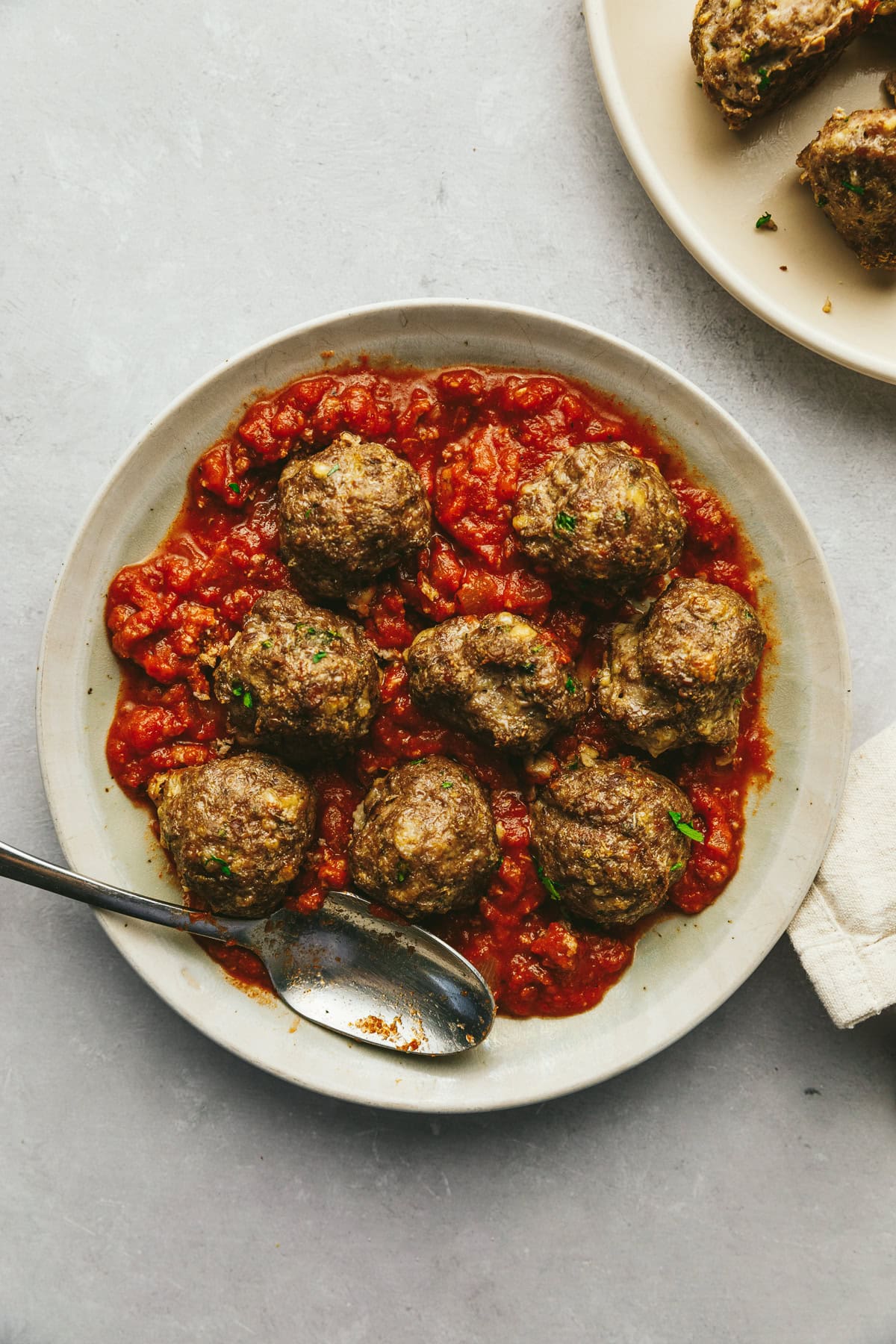 A plate of keto meatballs with a red marinara sauce.