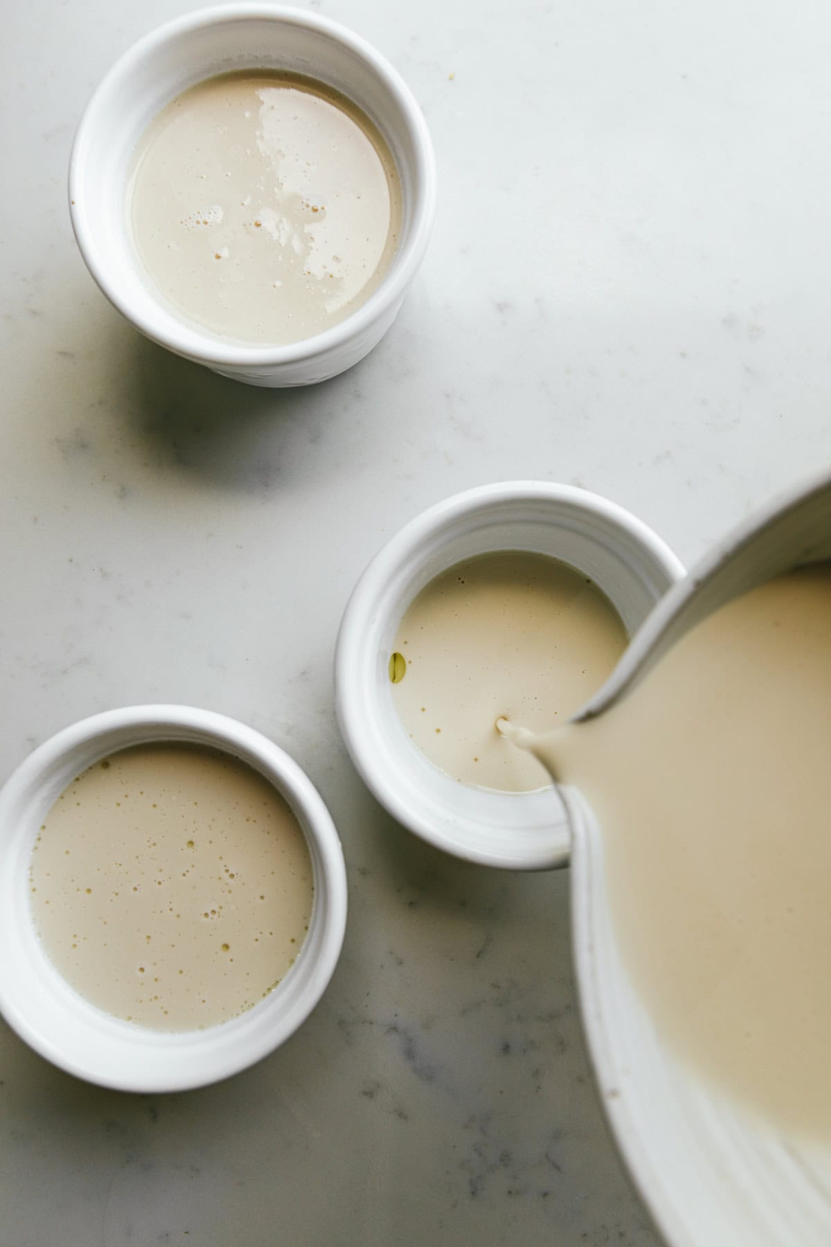 Pouring coconut panna cotta into ramekins.