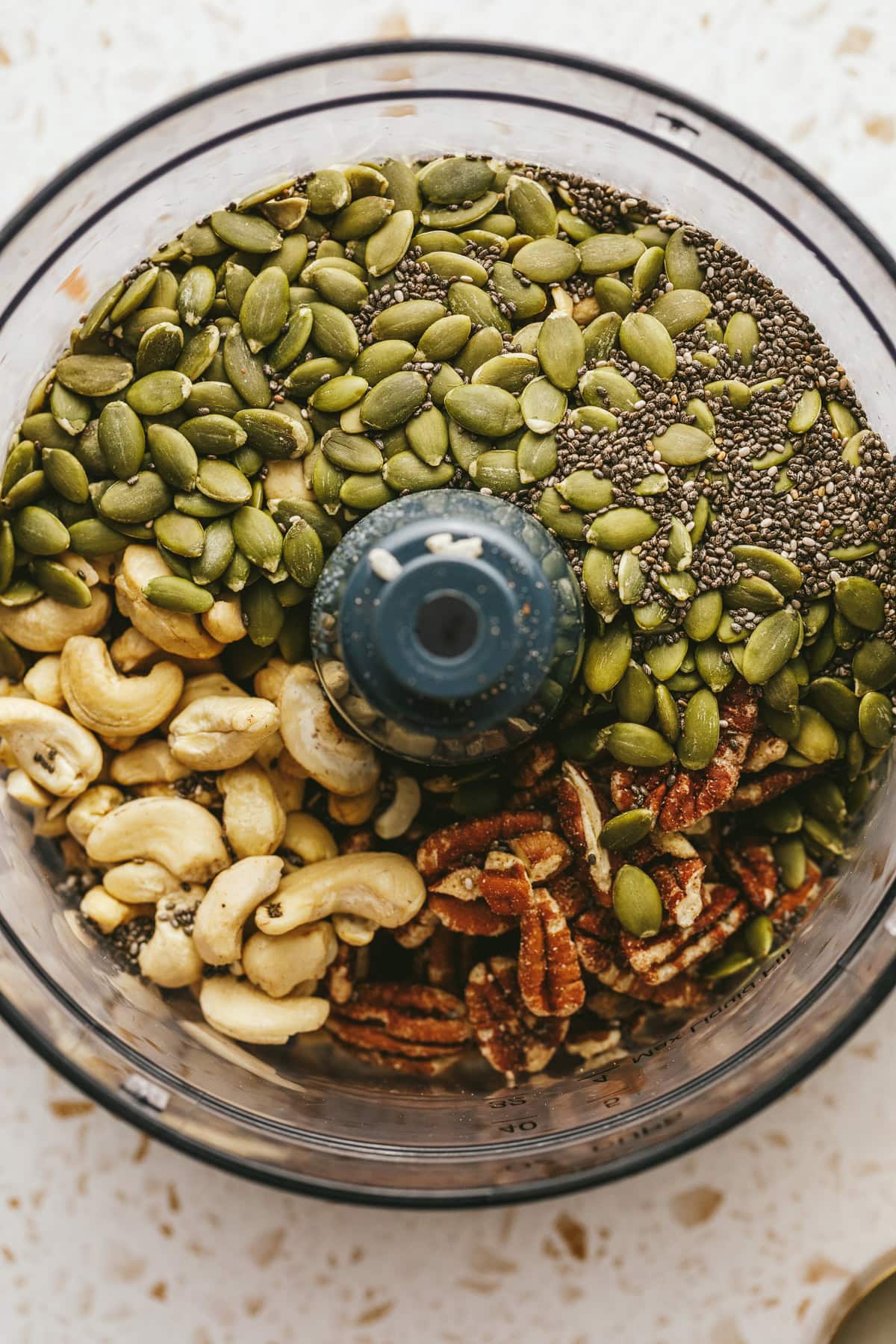 Nuts and seeds for grain-free vanilla almond butter granola in a food processor.
