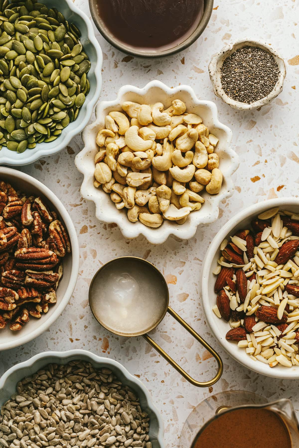 Ingredients on a marble surface for grain-free vanilla almond butter granola.