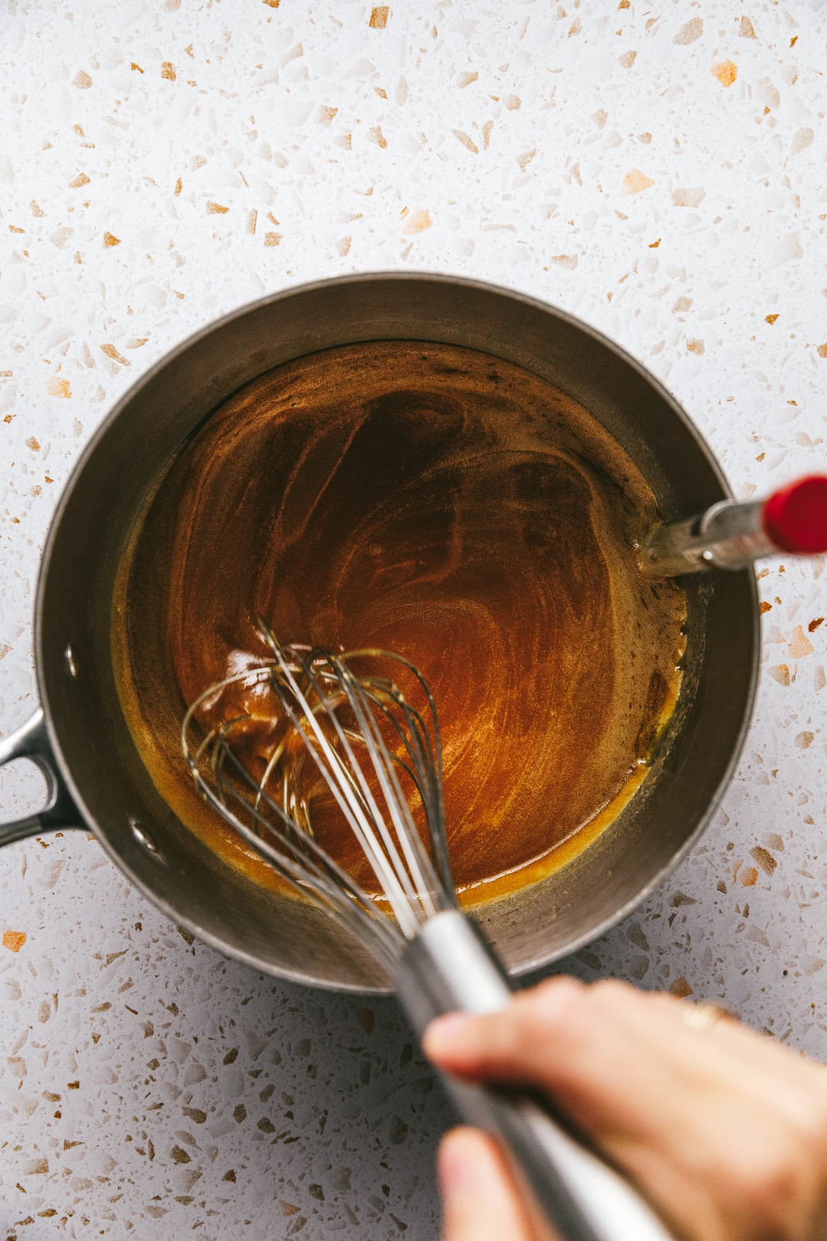 Whisking keto caramel mixture in a medium saucepan.