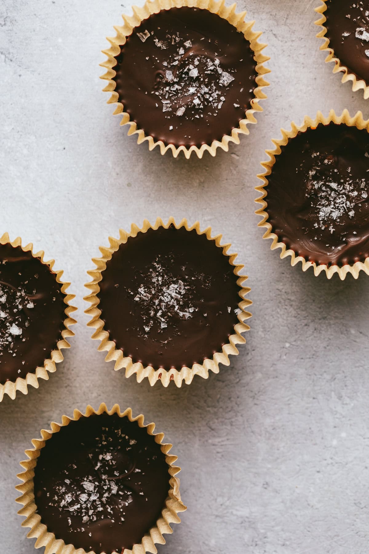 Dark chocolate almond butter cups on a gray surface.