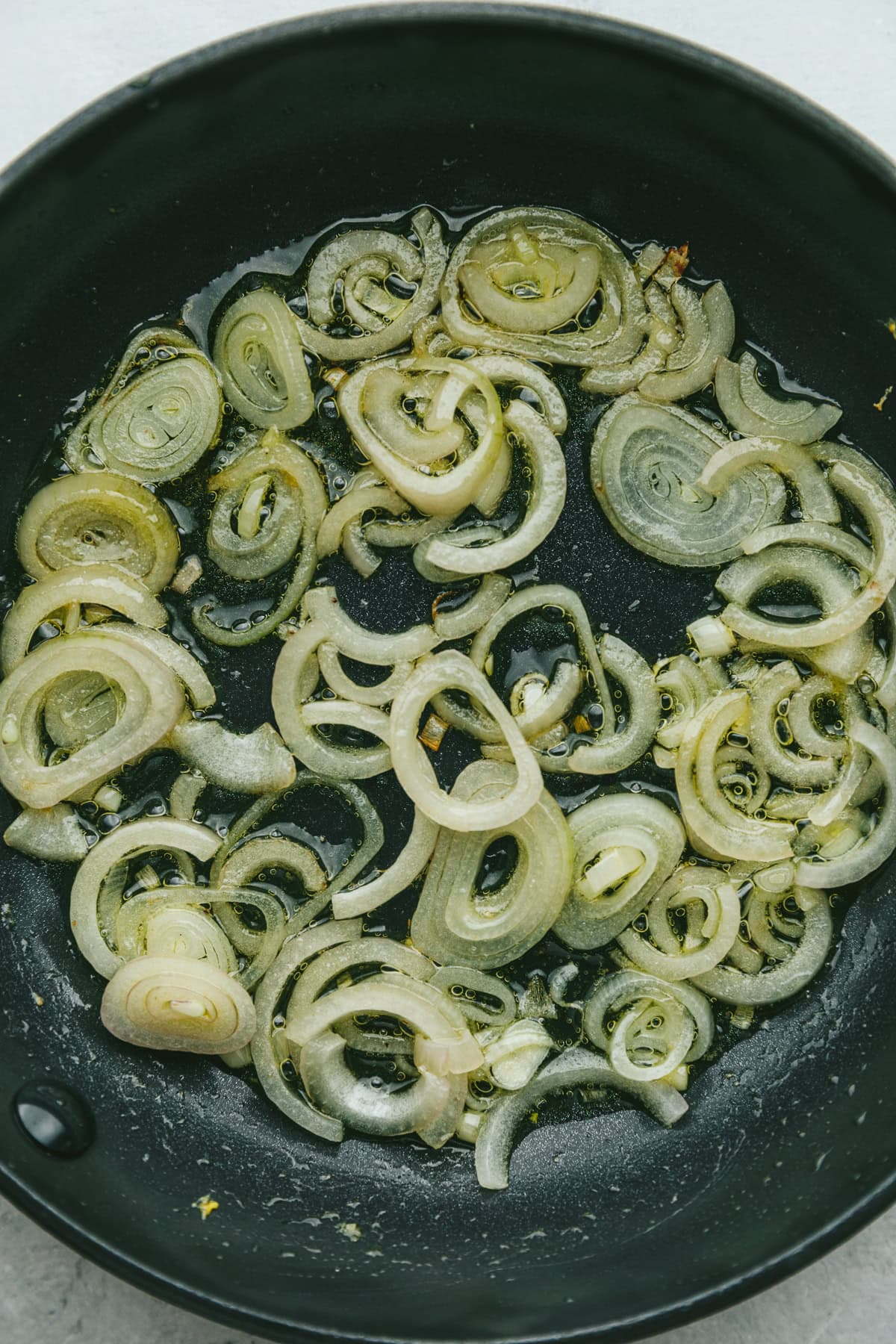Shallots frying in a black pan.