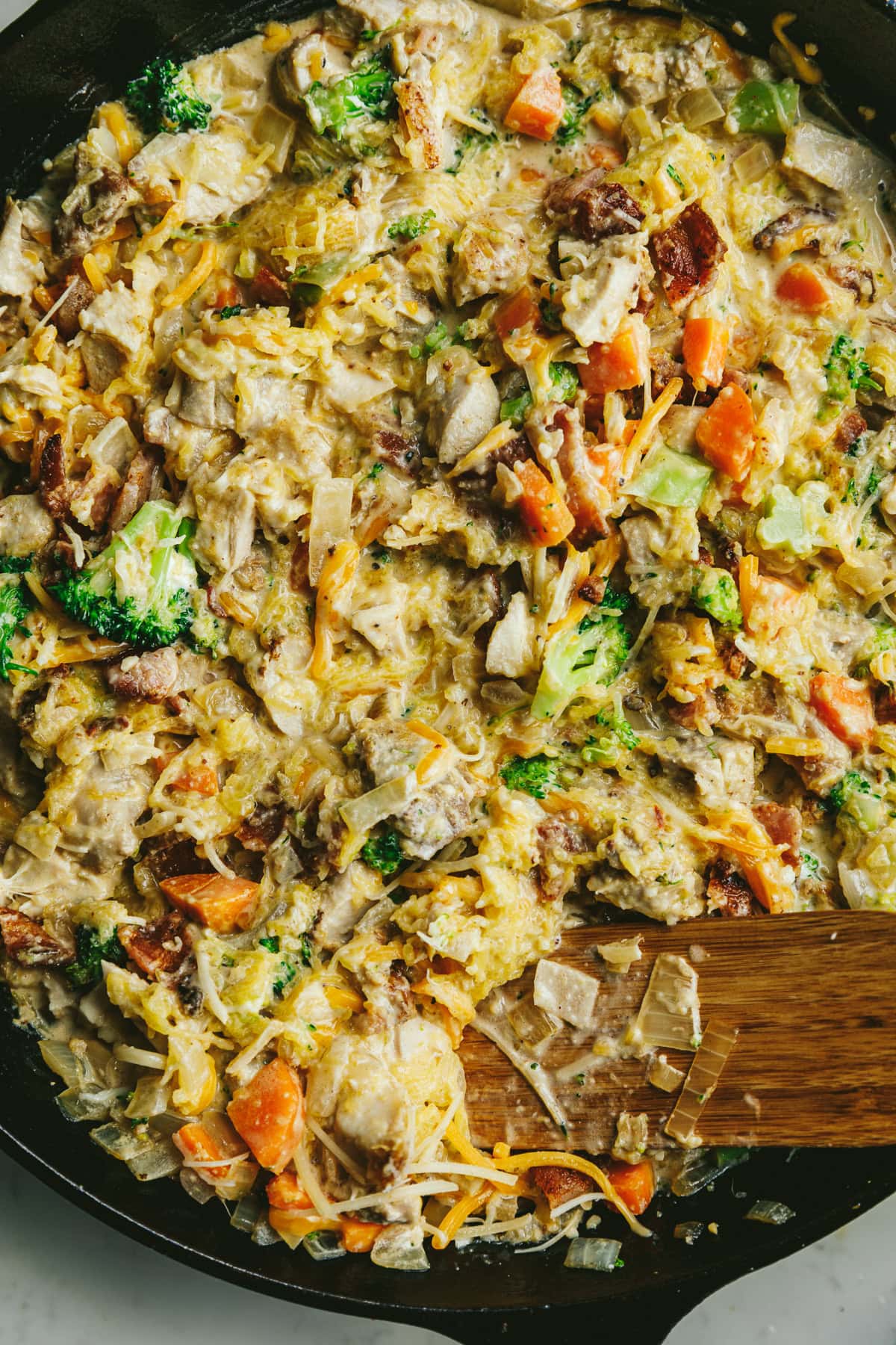 Alfredo chicken and broccoli bake with spaghetti squash in a skillet before baking.