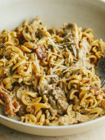 Chicken garlic parmesan pasta in a beige bowl with a fork.