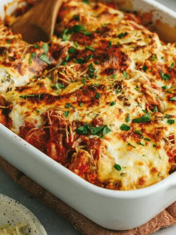 Cooked million dollar spaghetti squash casserole with a wooden serving spoon.