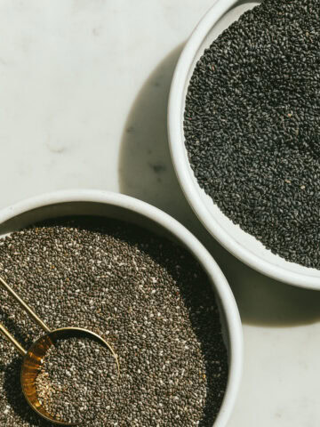 Chia seeds and sweet basil seeds, each in a white bowl.