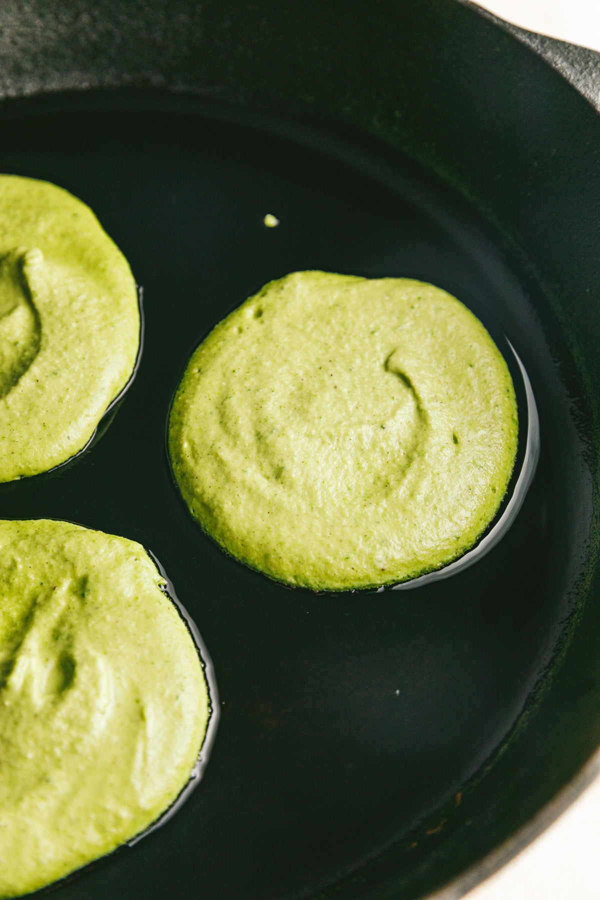 Banana spinach pancakes in a black cast iron skillet.