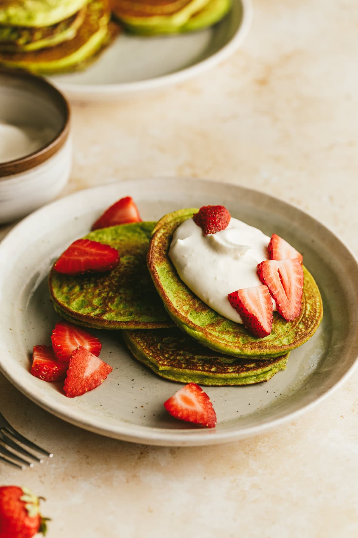 A stack of banana spinach pancakes with yogurt and berries.
