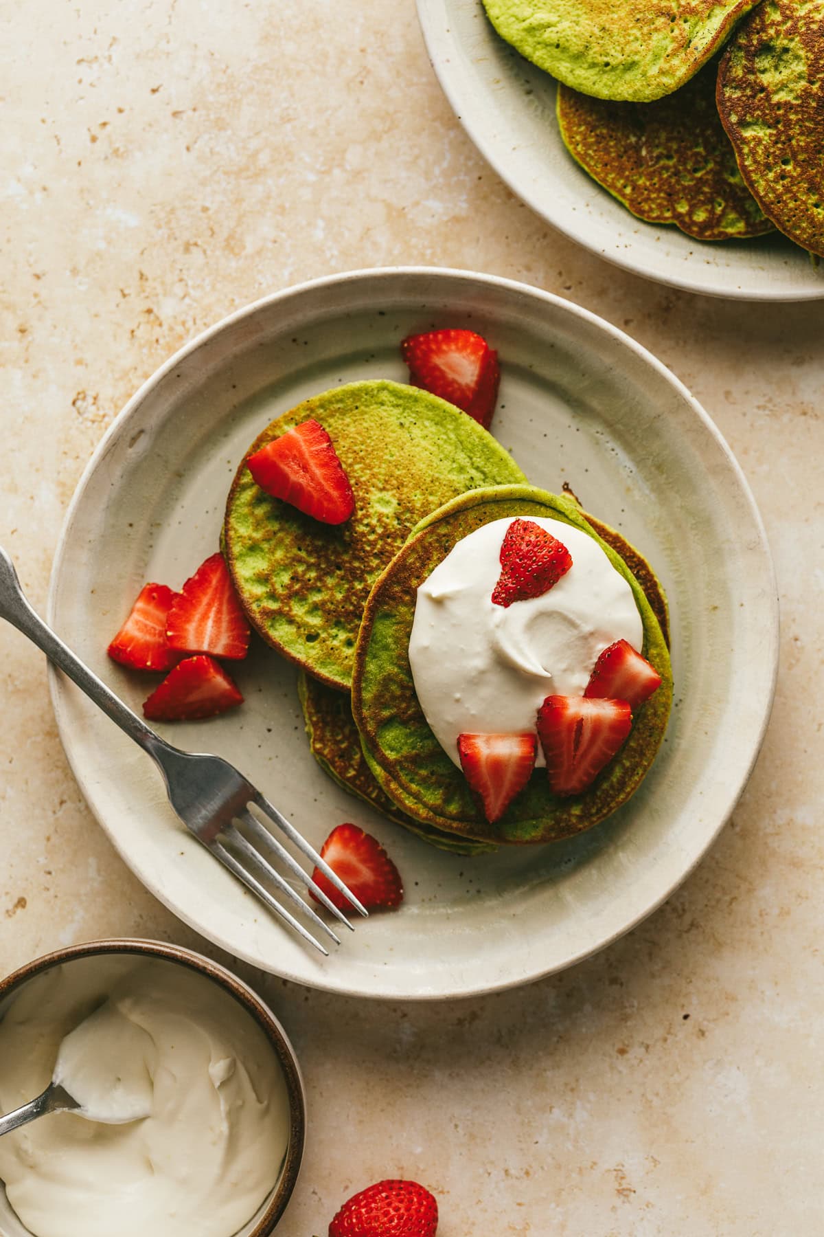 A plate with banana spinach pancakes and toppings.