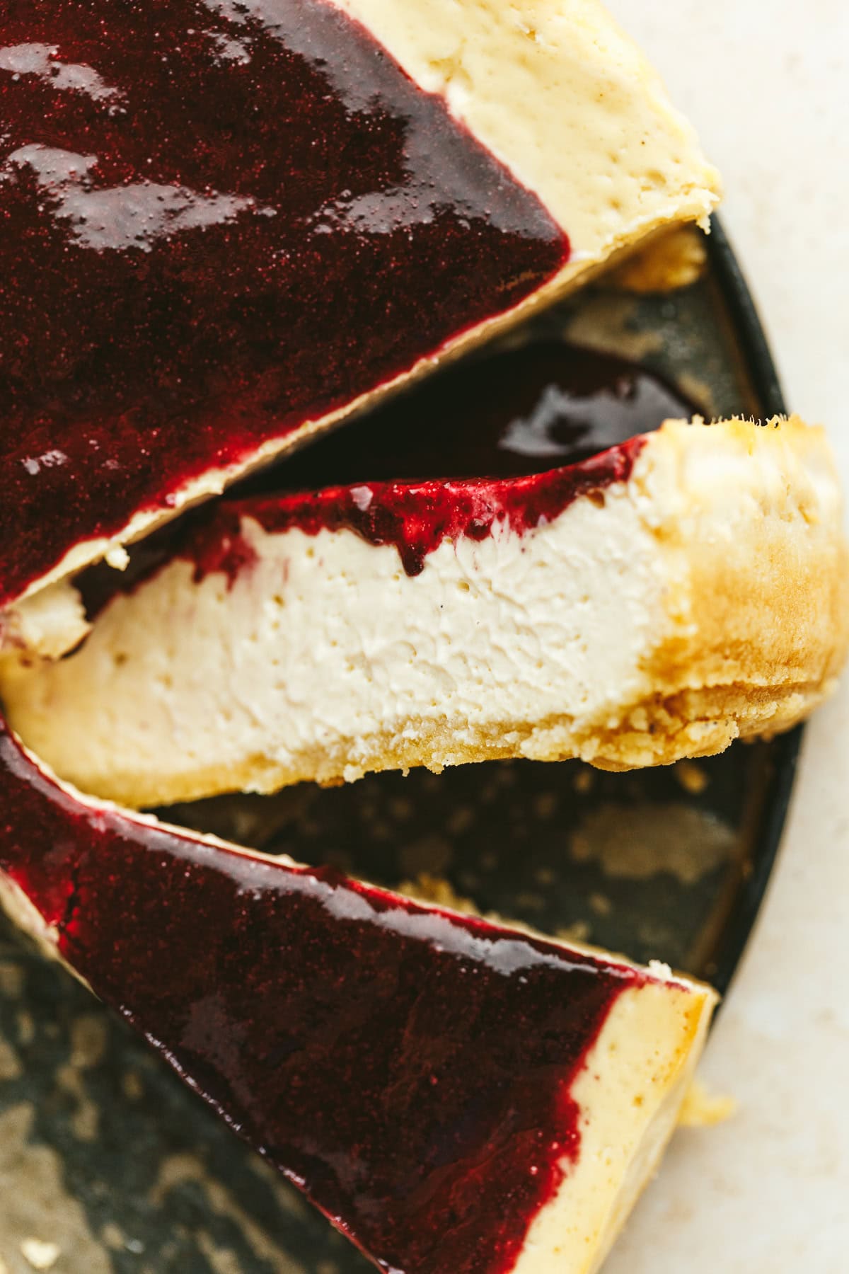 A slice of high-protein cheesecake with berry sauce.