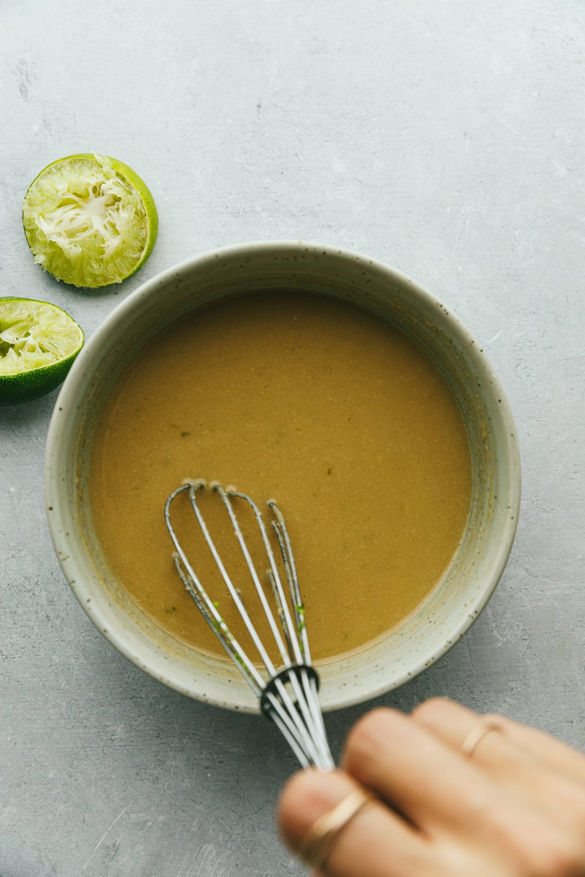 Whisking the ingredients for lime tahini dressing in a bowl.
