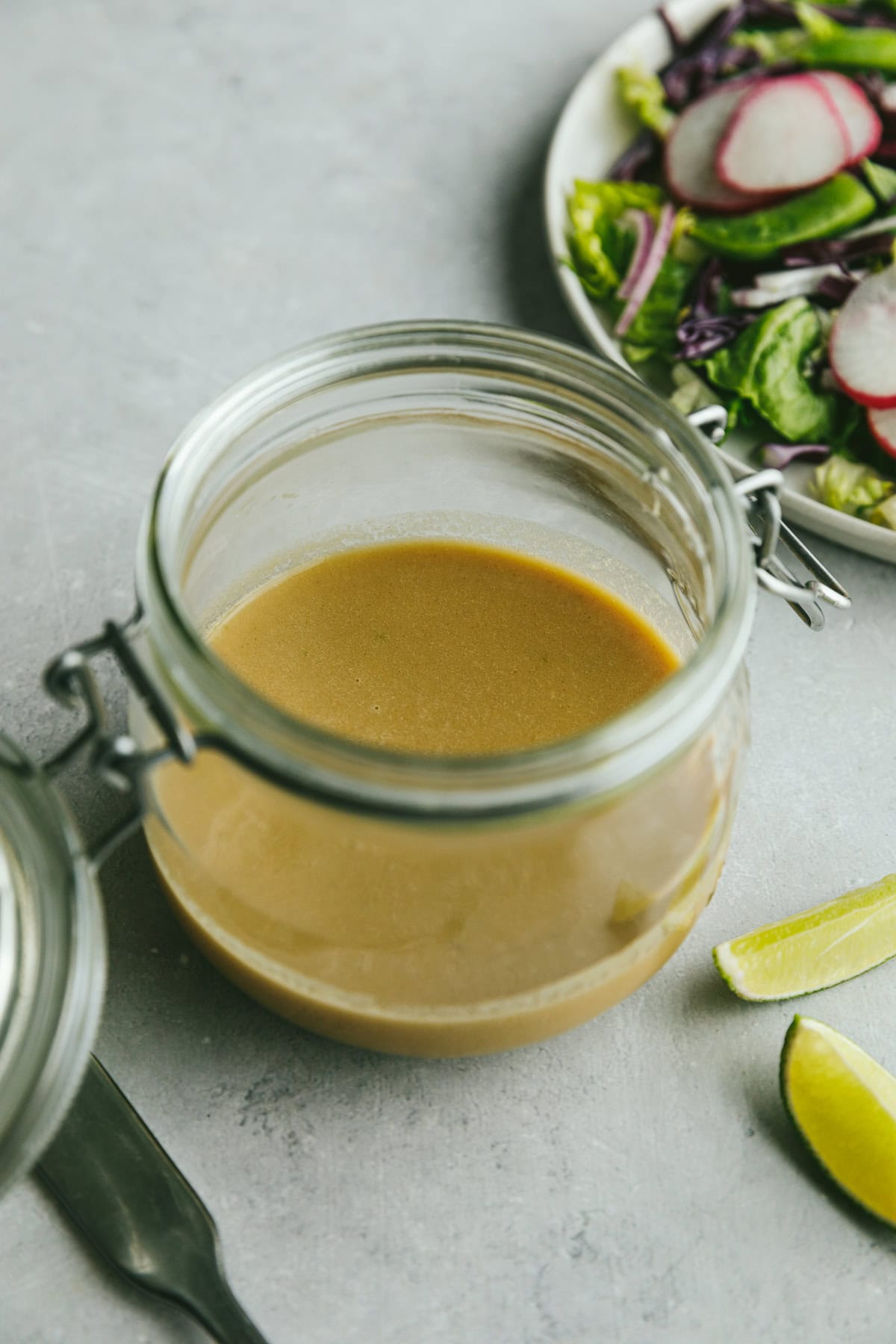 A glass storage jar of lime tahini dressing.