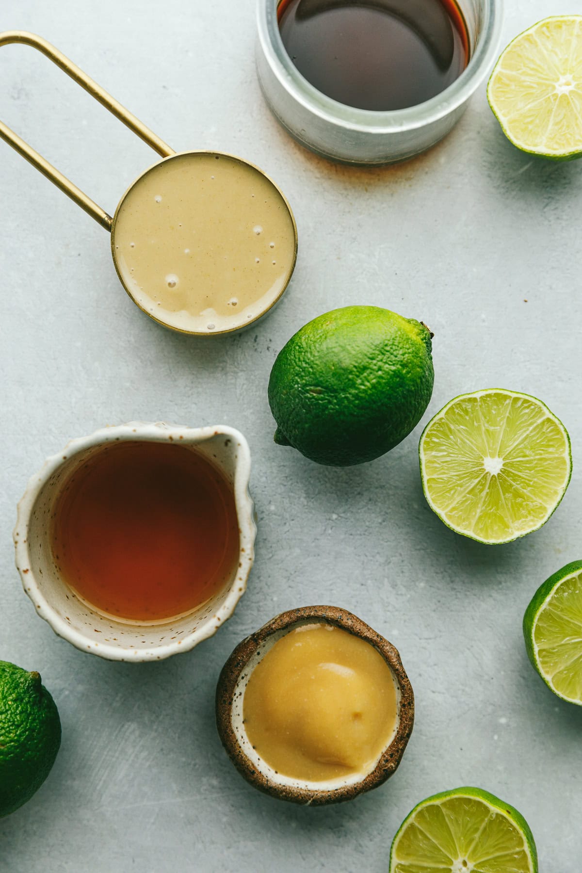 Ingredients for tahini lime dressing on a gray marble surface.