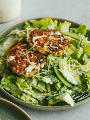 Tuna Caesar salad with a fork and caesar dressing behind it.