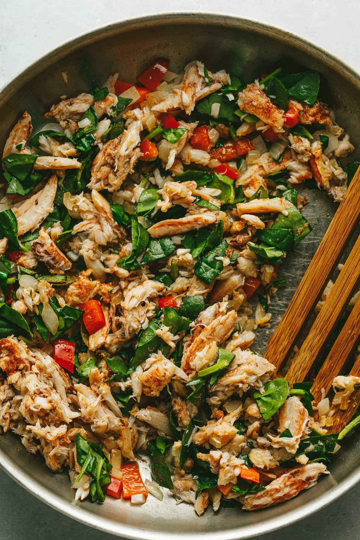 Veggies and crab cooked in a stainless steel skillet.