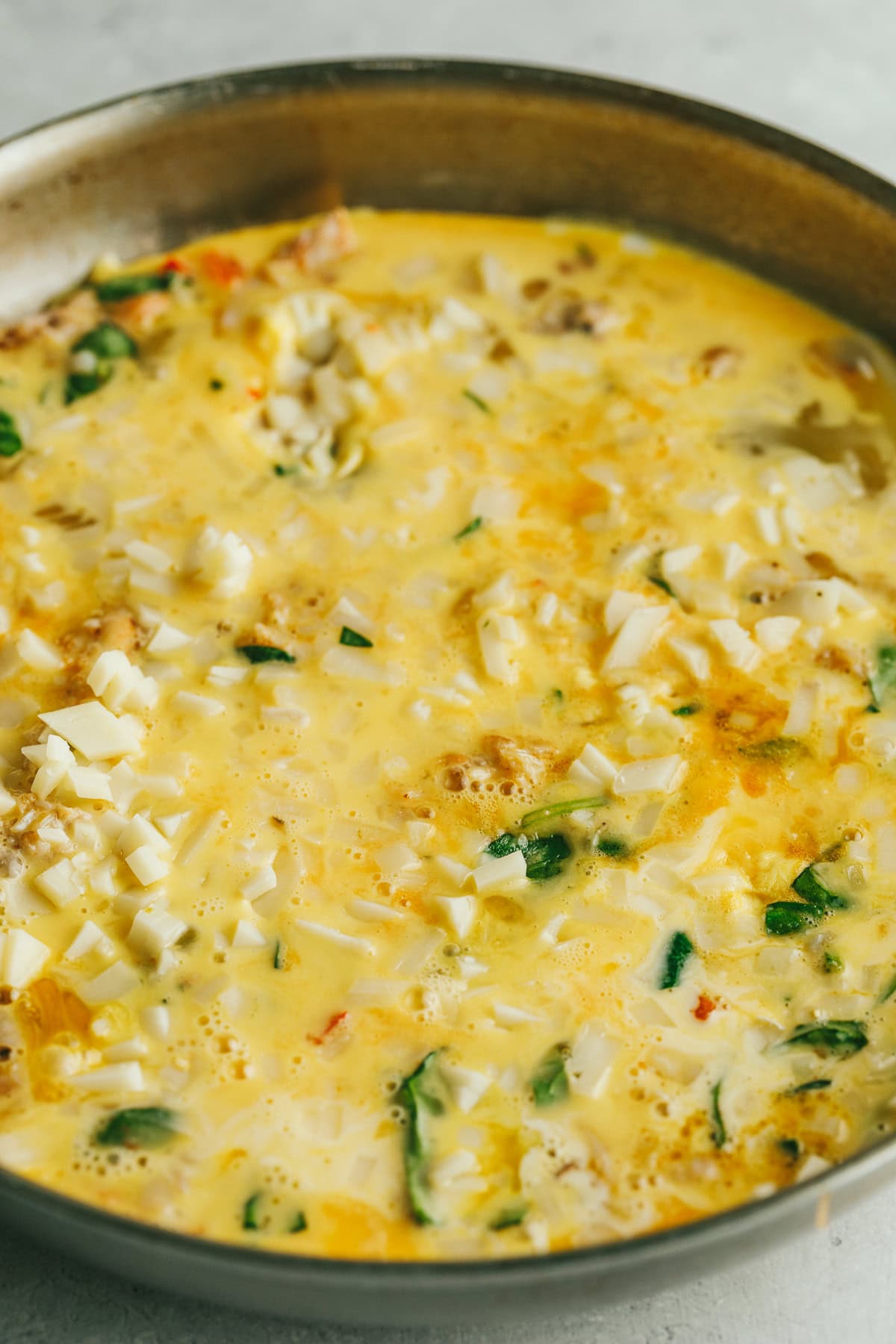 Crab frittata in a stainless steel pan before baking.