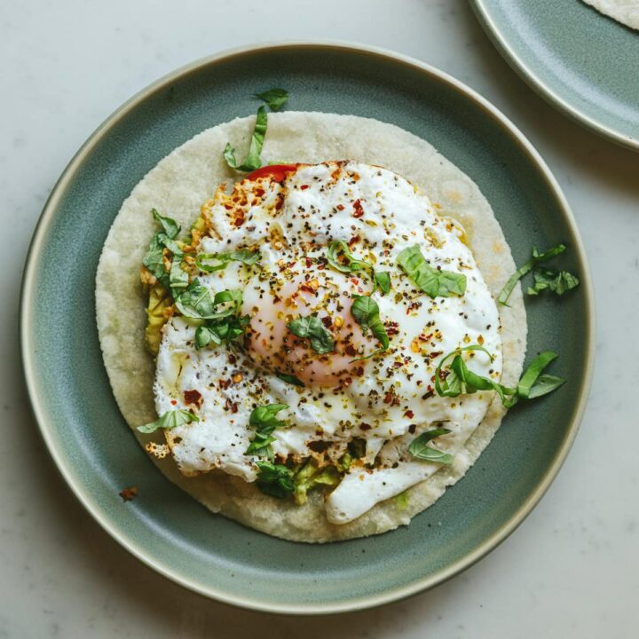 A feta fried egg on a green plate with basil.