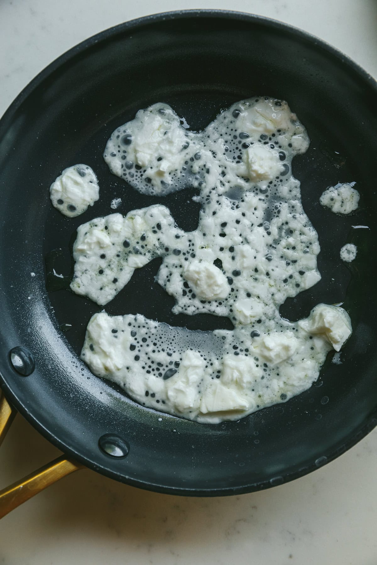 Crumbled feta in a hot pan melting.
