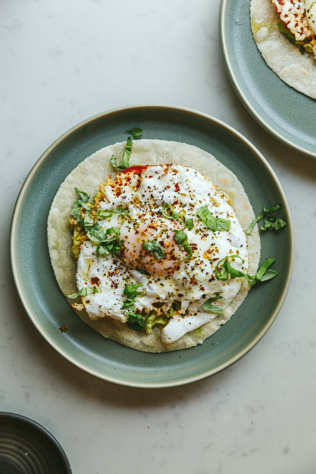 Feta fried eggs on a green plate with toppings.