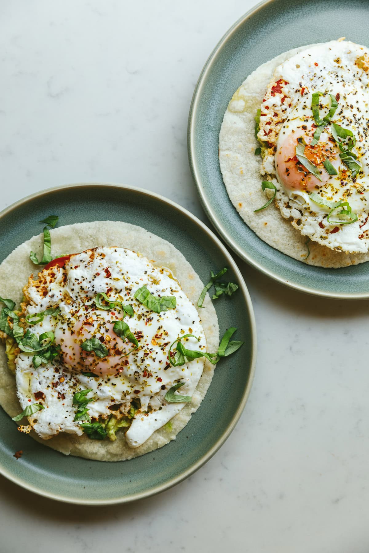 Two plates with feta fried eggs on tortilla.