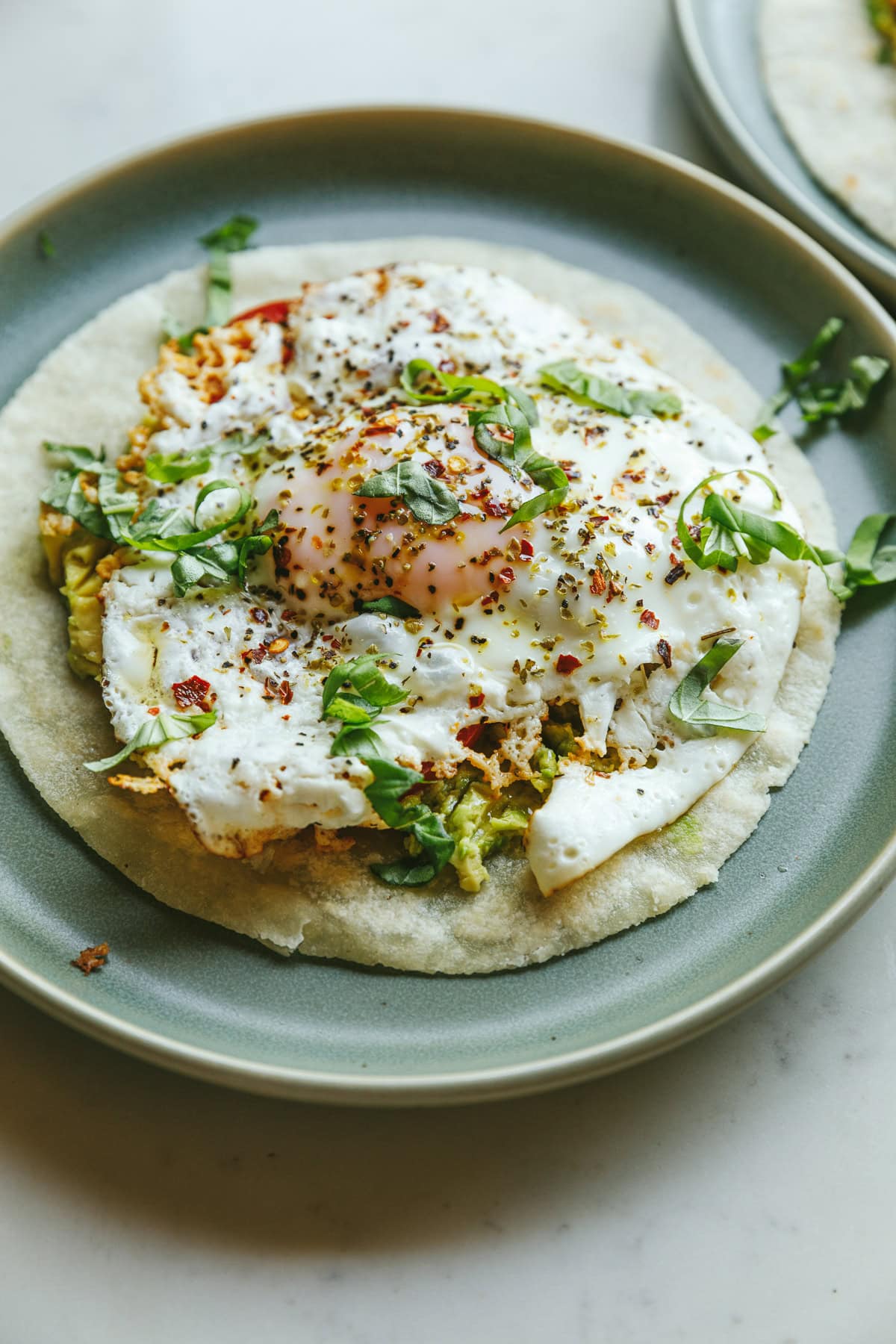 A plate with a feta fried egg and chopped basil.