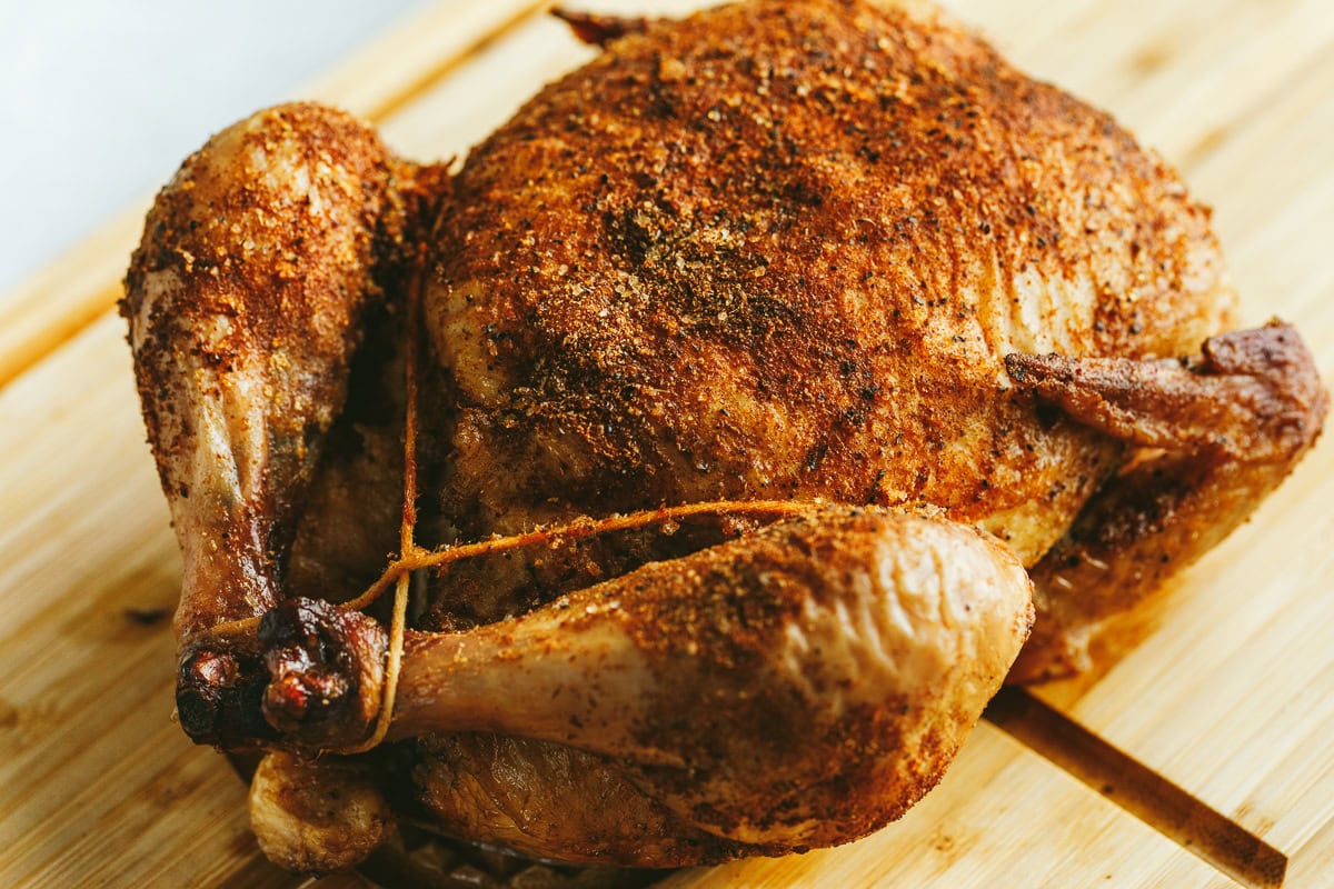 Whole Traeger smoked chicken on a carving board.