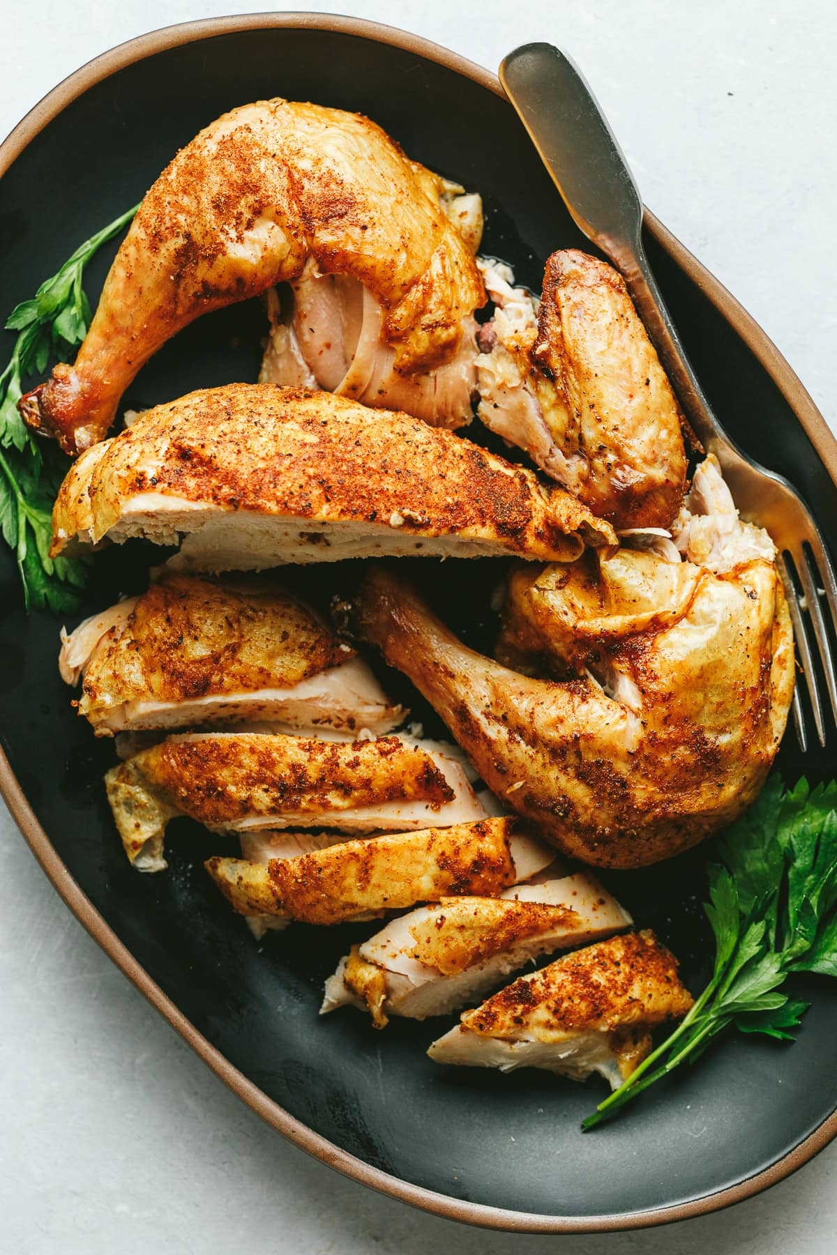 A carved Traeger whole chicken on a black platter.