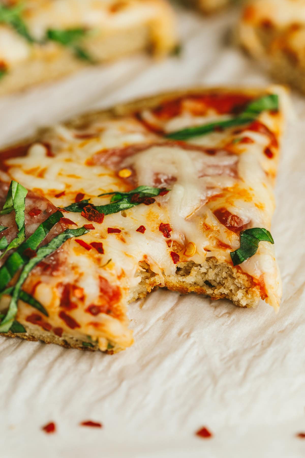 A closeup shot of a bite taken out of a grain-free pizza.
