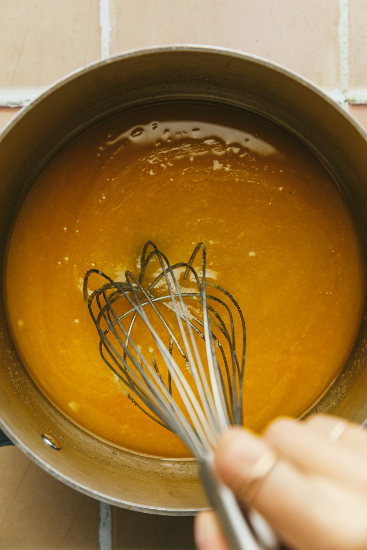 Whisking caramel sauce ingredients together in a saucepan.