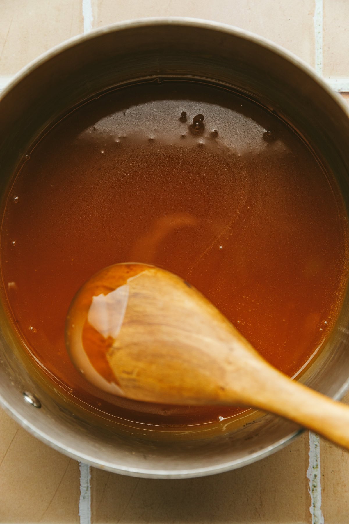 Stirring keto caramel sauce in a saucepan.
