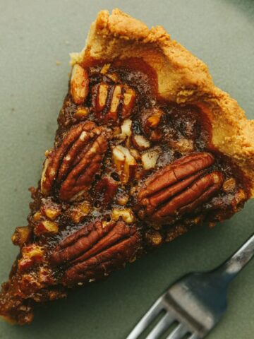 A slice of keto pecan pie with a fork on a green plate.