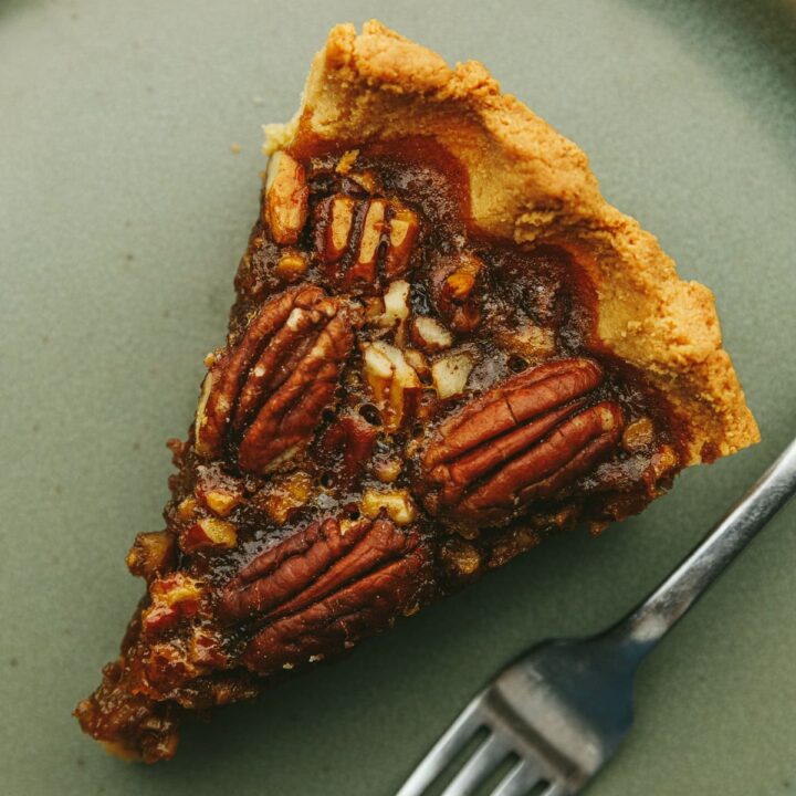 A slice of keto pecan pie with a fork on a green plate.